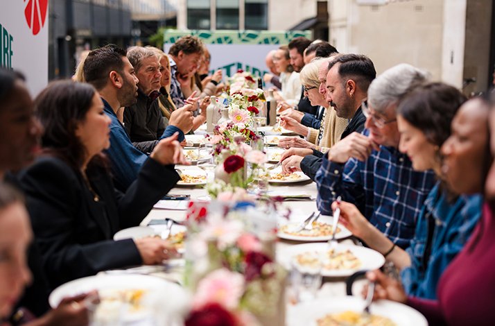 A long outdoor dining table is filled with people enjoying a meal at Future of Food's Sustainable Safari.
