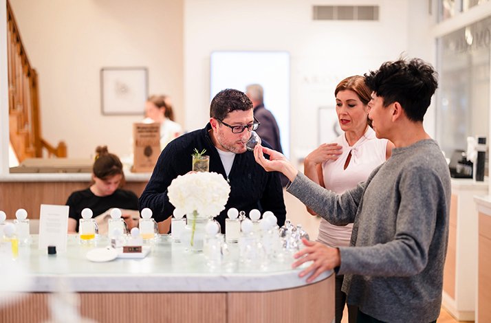 In a bright, modern Aromaria boutique, a group of people are engaged in a fragrance-smelling experience.