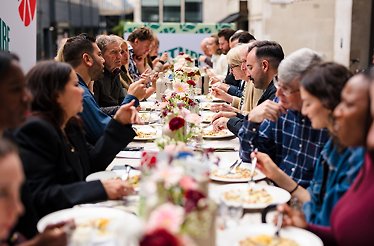 A long outdoor dining table is filled with people enjoying a meal at Future of Food's Sustainable Safari.