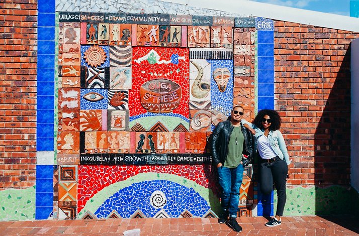 Two people taking a picture with a mural in Cape Town.