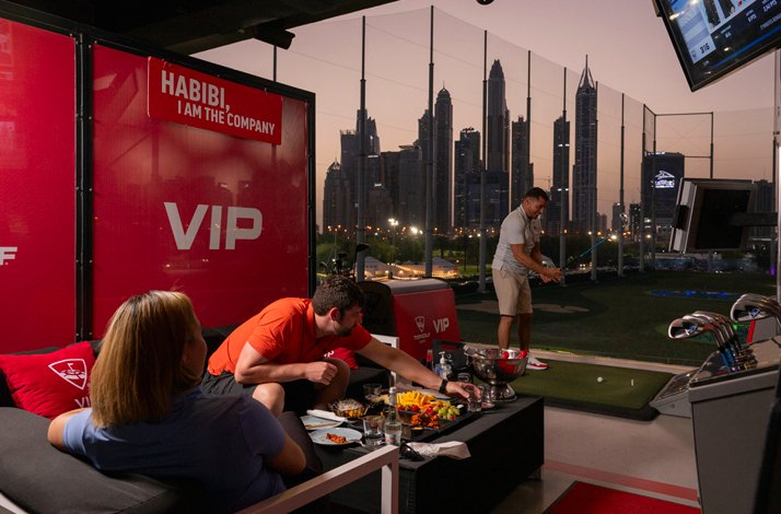 Visitors immersed in a high-tech golf game on upper floor of Premium Bay at TopGolf in Dubai.