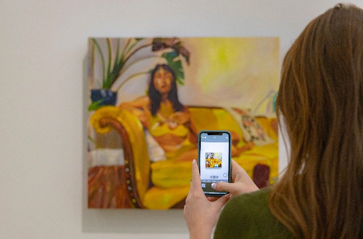 A girl takes a photo of the painting Seeds by Gisela McDaniel at the Pérez Art Museum Miami.