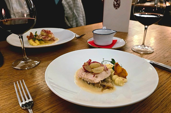 A set table with two dishes and glasses of wine.