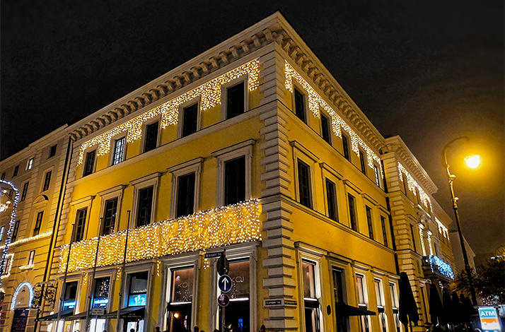 Outside photo of KOI Restaurant at night decorated with traditional Christmas Lights