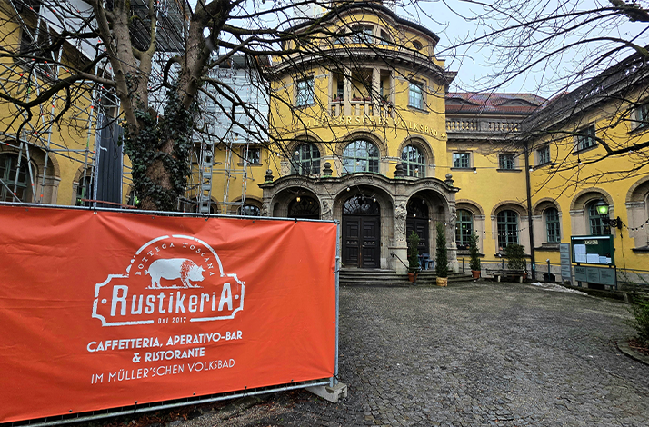 Banner advertising restaurant Rustikeria in front of Müller'sches Volksbad in Munich, Germany.