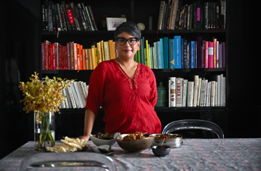 Vasunthara Ramasamy in front of her book shelves at her home. 