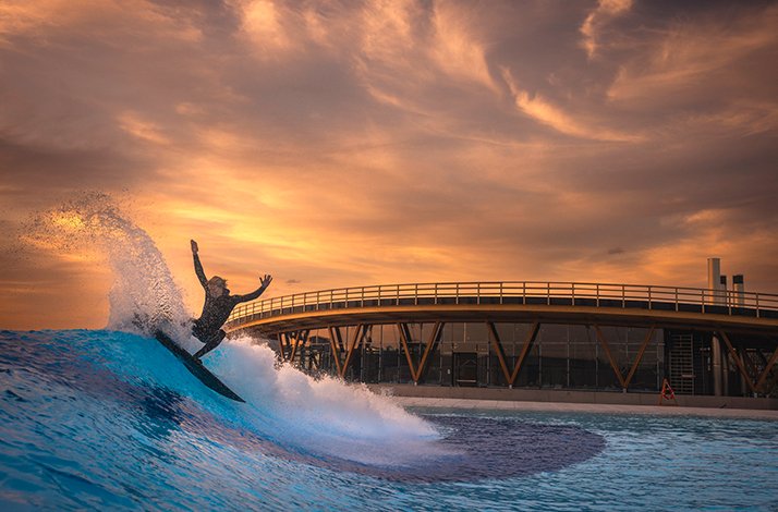 Person riding a wave at sunset during surf session at O2 Surftown in Munich, Germany.