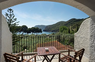The Balcony with wooden table and chairs overlooking the sea at Hotel Cala Jóncols