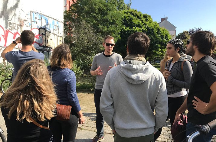 A guide explaining street art to a group of young people.