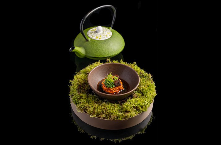 A green teapot featuring a bowl with a dish.