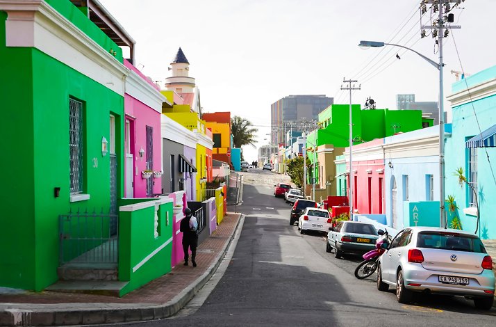 A street in Cape Town with brightly colored buildings on both sides, including green, pink, yellow, and blue.