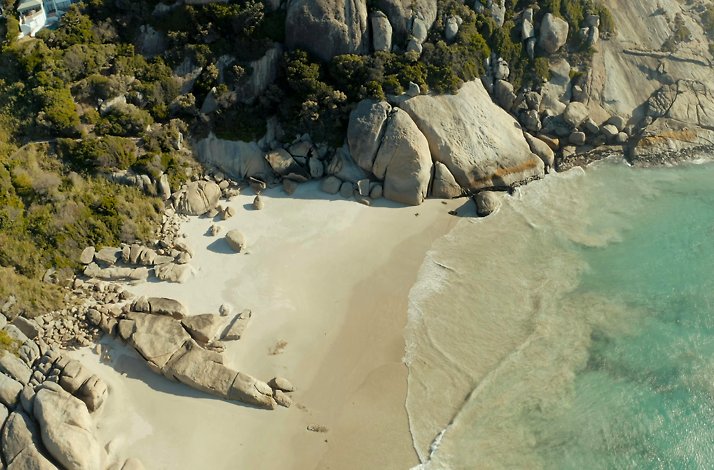 Captivating aerial image of a beach and rugged rocks, representing the adventurous allure of Cape Town, South Africa.