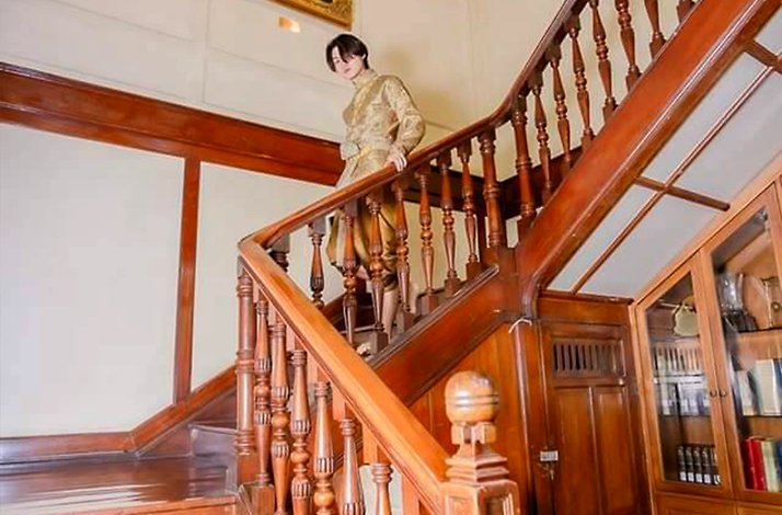 A man in traditional Thai costumes posing on a staircase at the Suan Sunandha Palace