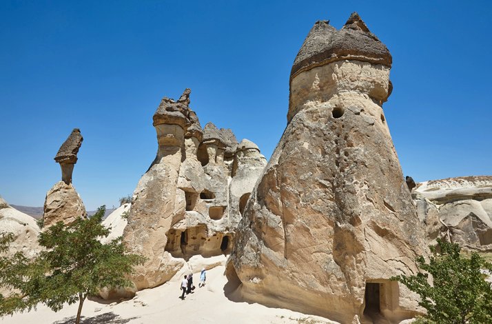 Rock formations at Paşabağ in Cappadocia, with visitors walking between the fairy chimneys.