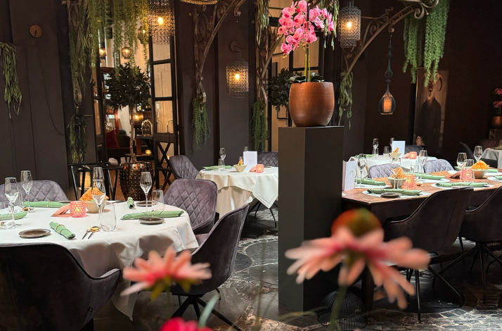 Elegant restaurant dining room in Rura with white-clothed tables, black leather chairs, table lamps, and framed art on the wall.