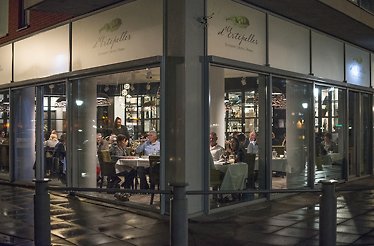  An outdoor dining area of a De Ertepeller restaurant at night, with guests.