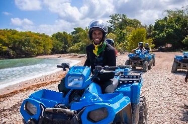 A man is sitting on a blue ATV during Tour through Jamaica's Landscapes