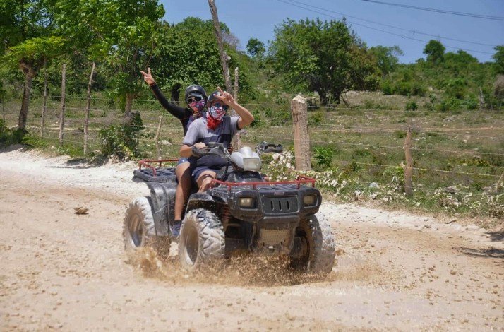 Two people riding an ATV on a country road in Punta Cana