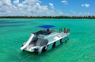 A party boat in the ocean, surrounded by clear blue waters and a bright sky.