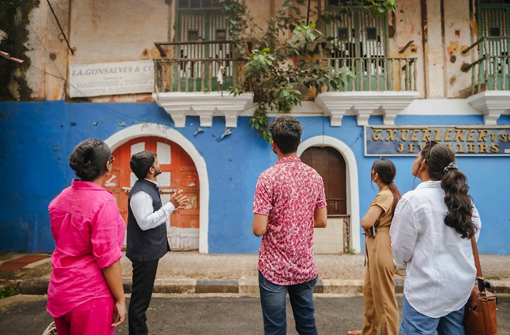 Five tourists standing in front of a blue house in Fontainhas - Asia's oldest Latin Quarter in Panaji, India.