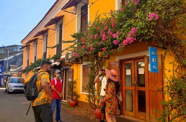 Four tourists standing in front of a yellow house in Fontainhas - Asia's oldest Latin Quarter in Panaji, India.