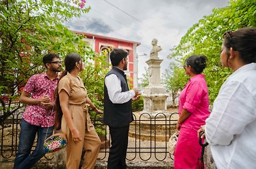 Five tourists looking at a monument during tour around Fontainhas - Asia's oldest Latin Quarter in Panaji, India.