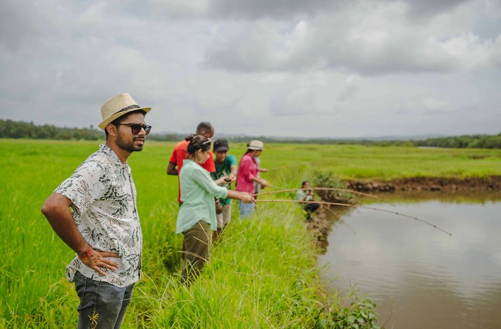 A man looking at the river with a group of people fishing in the background.