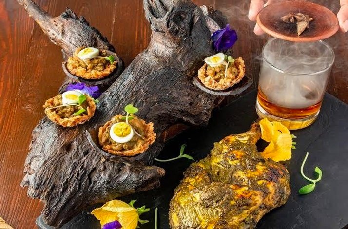Meat dishes from seasonal farm-to-table menu served on tree trunk.