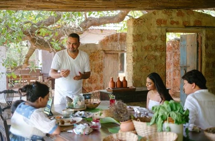 Chef Avinash Martins talking with participants around the outdoor dining table.