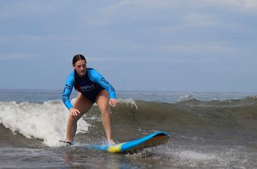 A person in a blue wetsuit surfing at the Manuel Antonio Beach at Costa Rica.