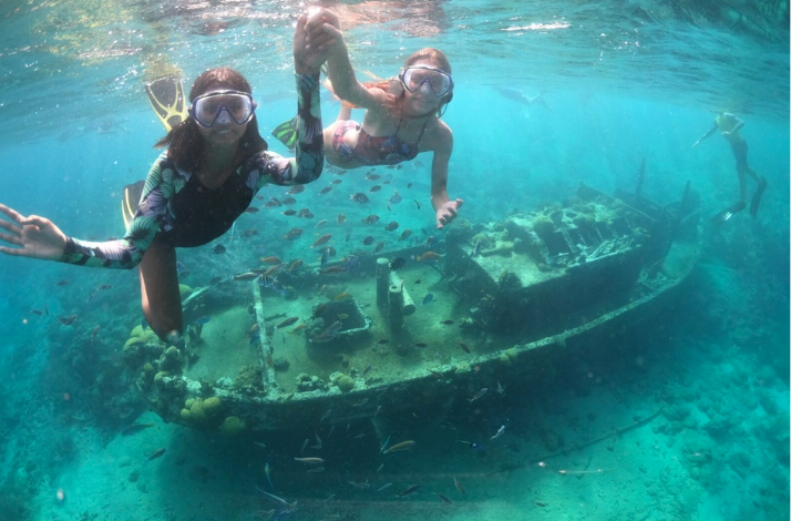 People snorkeling next to a shipwreck in Caracas Bay.
