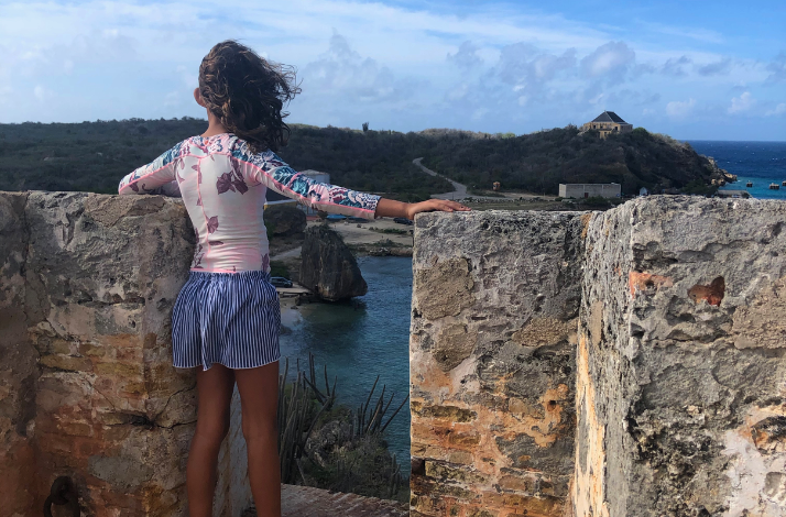 A young kid overlooks the view of the sea off the Fort Beekenburg. 