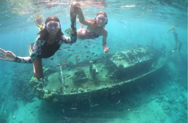 People snorkeling next to a shipwreck in Caracas Bay