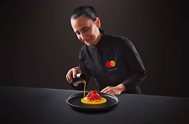 The chef wearing the uniform with the branded MC logo in the process of preparing the dish.