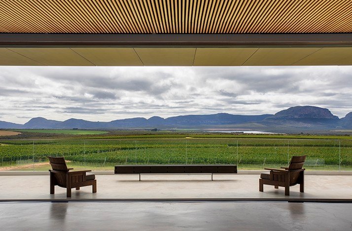 Spacious veranda with comfortable armchairs looking at large garden of grape trees at Winery UVVA.