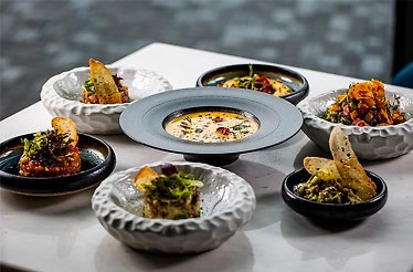 A dining table set with multiple bowls of Italian dishes at Bavette Italian Steakhouse at Bucharest.