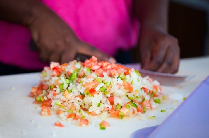 A person cutting fresh vegetables to cook an authentic conch salad