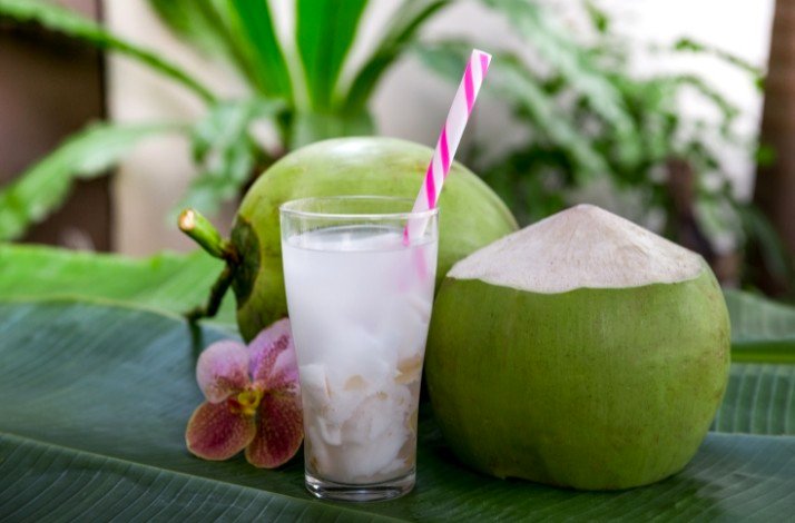 A refreshing coconut water drink with a straw placed beside the coconut.