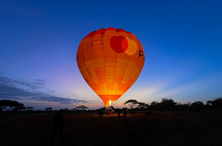 A brightly illuminated air balloon with the Priceless logo floating above the Amboseli national park.