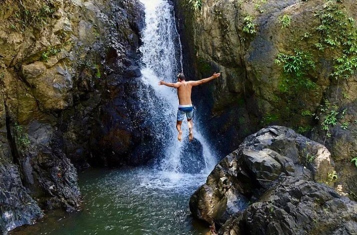 A person jumping into a secluded waterfalls at El Yunque Rainforest.