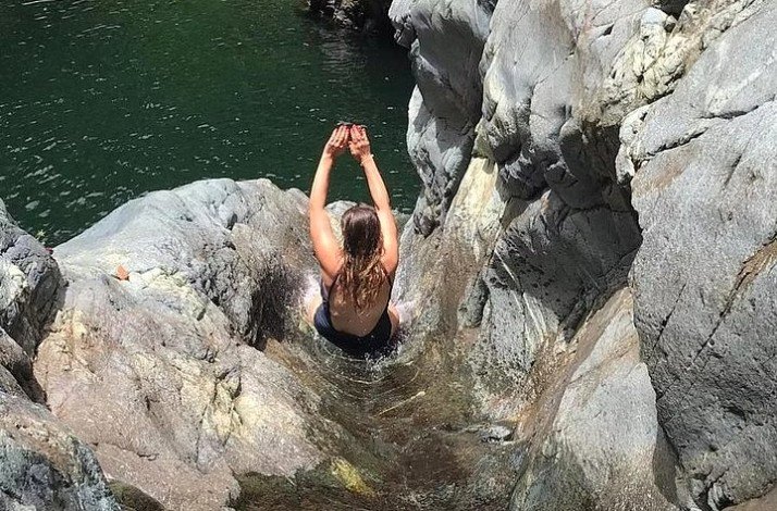A person sliding down a rock waterslide at Puerto Rico's famed El Yunque rainforest.
