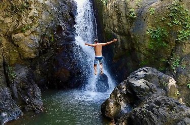 A person jumping into a secluded waterfalls at El Yunque Rainforest.