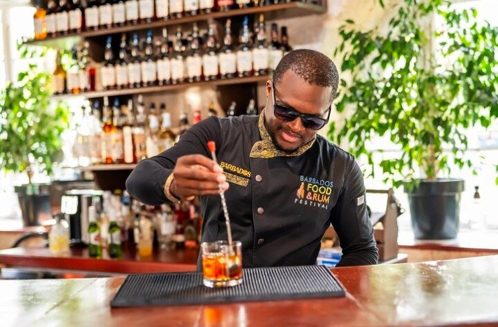 A barman from barbados food&rum festival  mixing a cocktail and smiling
