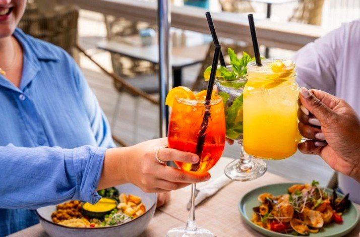 Three individuals are toasting their cocktail glasses at the Sand Street Bistro.