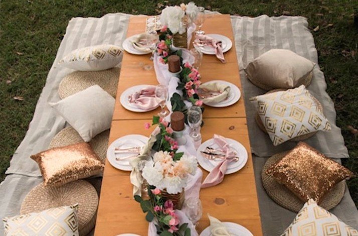 A picnic table decorated in white and gold pillows and flowers at Barbados.
