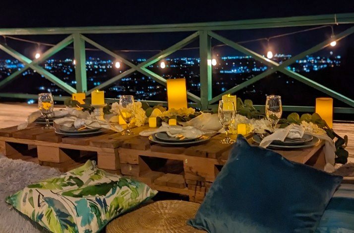 Dinning table arranged at balcony during night time with a city view.