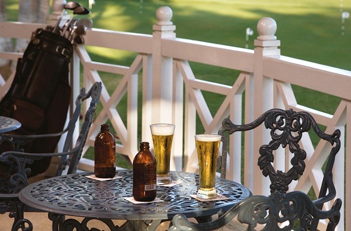 Two glasses of beer put on a table near golf area