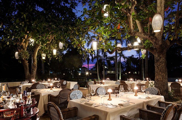 A group of tables set up at the Half Moon Hotel in contact with nature, with a couple of trees around.