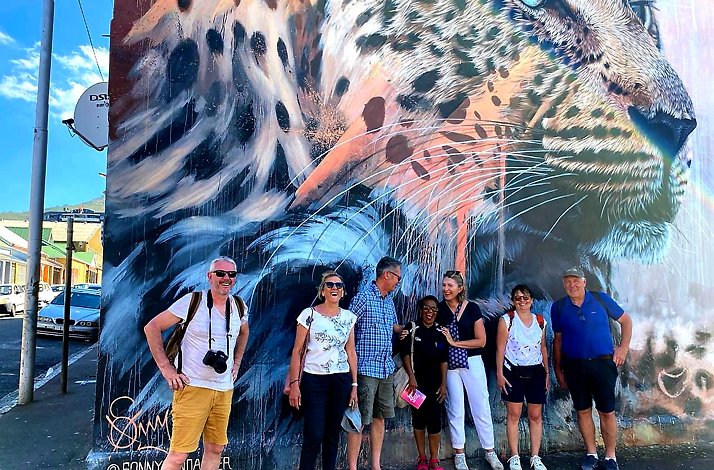 Tourists standing by the street art painting at the wall by the talented Caroline Jordaan at Cape Town.