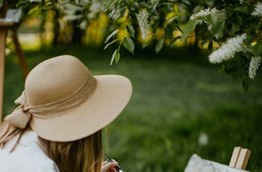 A person participating in a painting class at the garden with one-on-one guidance from the artist.